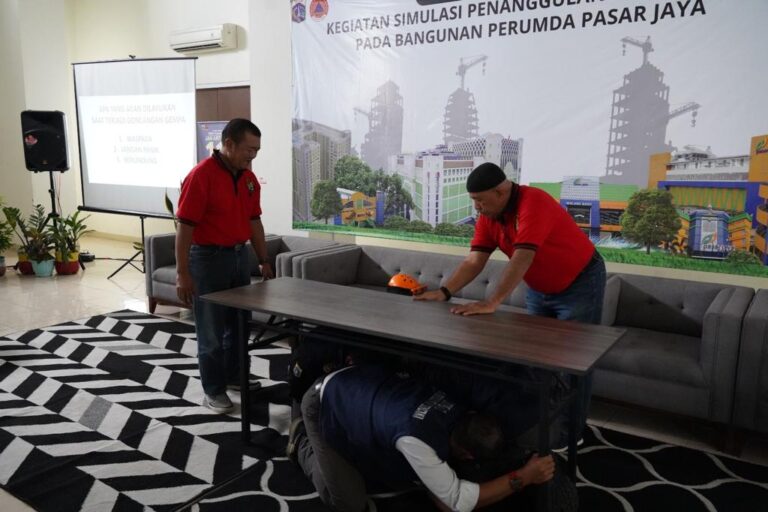 Seorang pegawai Perumda Pasar Jaya berupaya berlindung di bawah meja saat kegiatan simulasi penanggulangan bencana pada bangunan pasar yang terdampak gempa di kawasan Pasar Rumput, Pasar Manggis, Setiabudi, Jakarta Selatan, Selasa (4/7) siang. Foto: Pasar Jaya untuk ipol.id